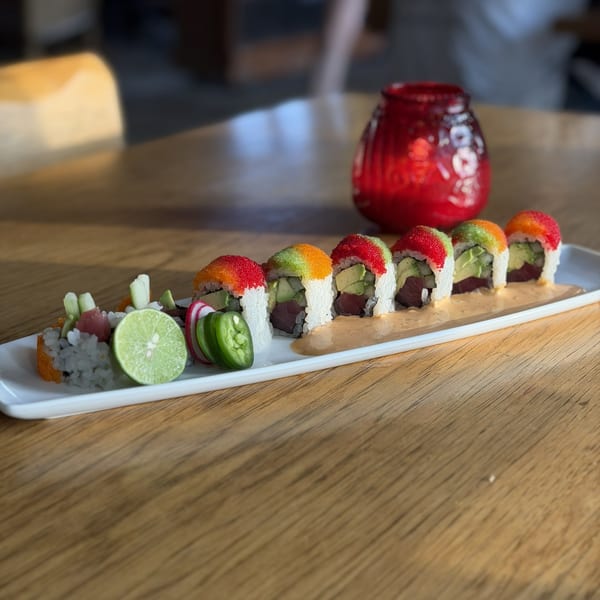 Colorful sushi rolls with avocado, tuna, and roe, garnished with lime and jalapeños.